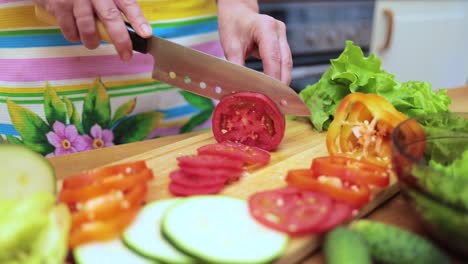 Women's-hands-Housewives-cut-with-a-knife-fresh-tomato-on-the-cutting-Board-of-the-kitchen-table